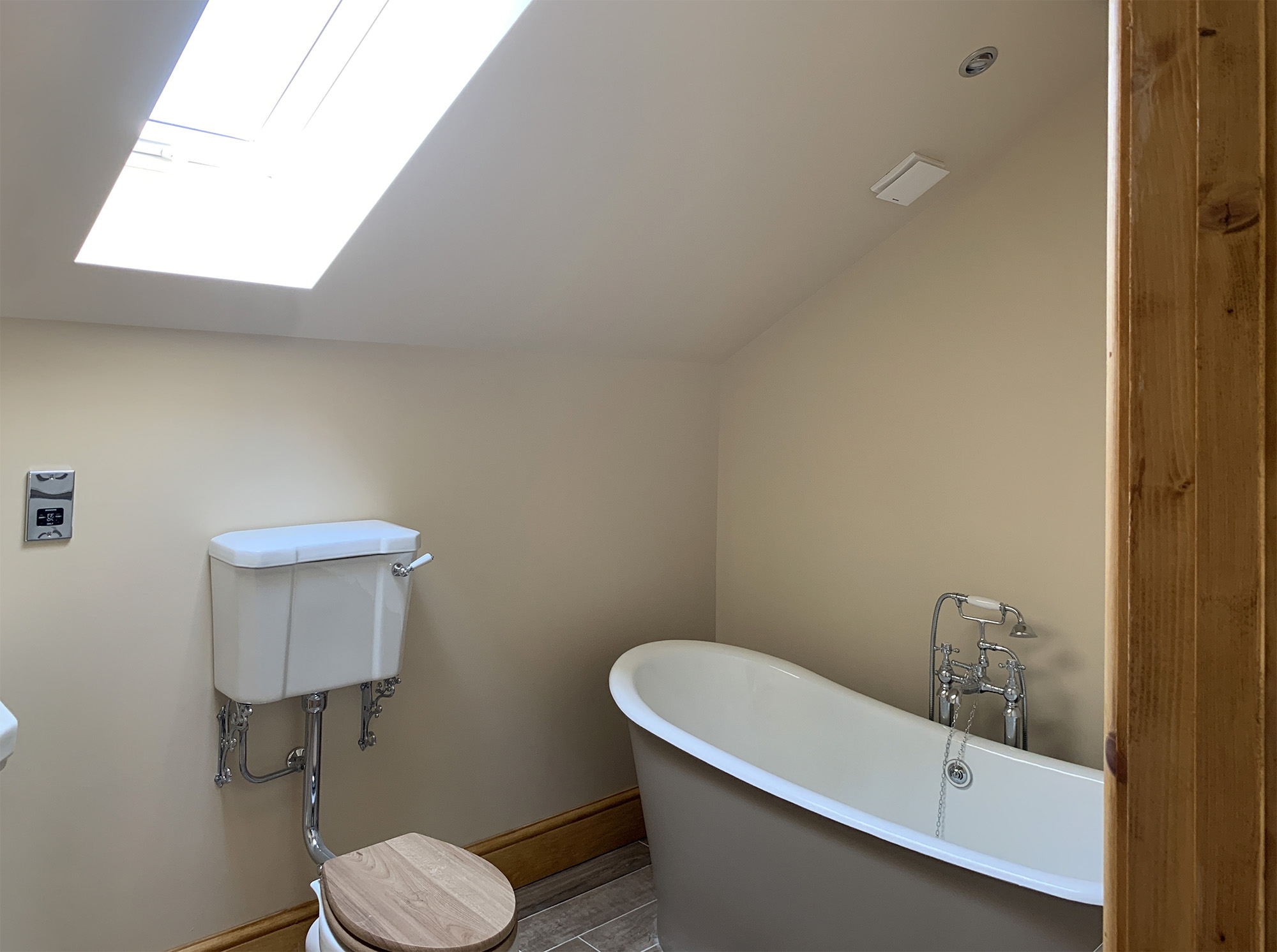 Newly plastered bathroom with pitched ceiling and skylight